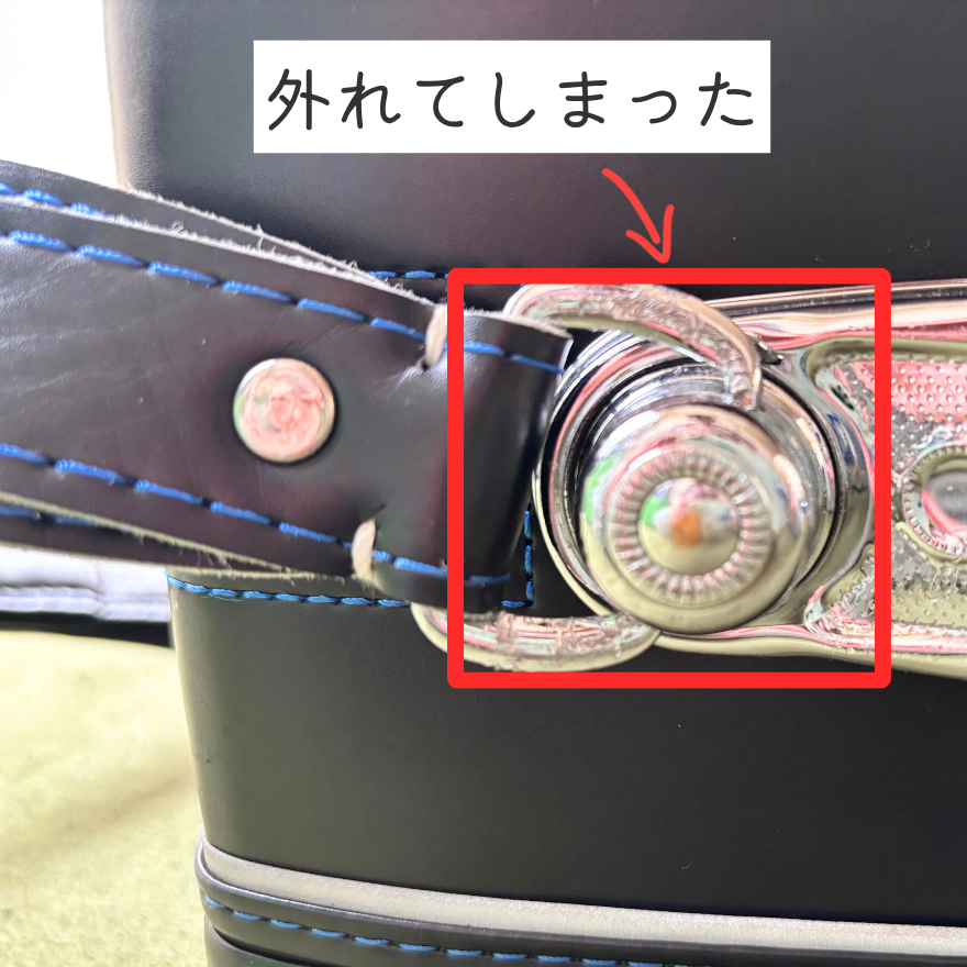 小学4年生のふわりぃ「スーパーフラッシュ」のランドセルを床に置いて、壊れた留め具部分を示している写真